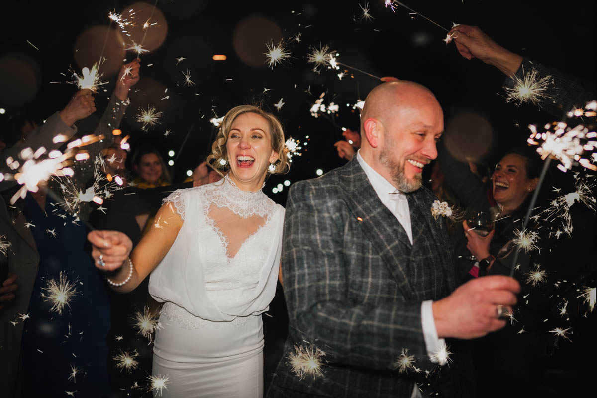 guests wave sparklers and hold them up high whilst the newly-weds walk through the aisle they've created