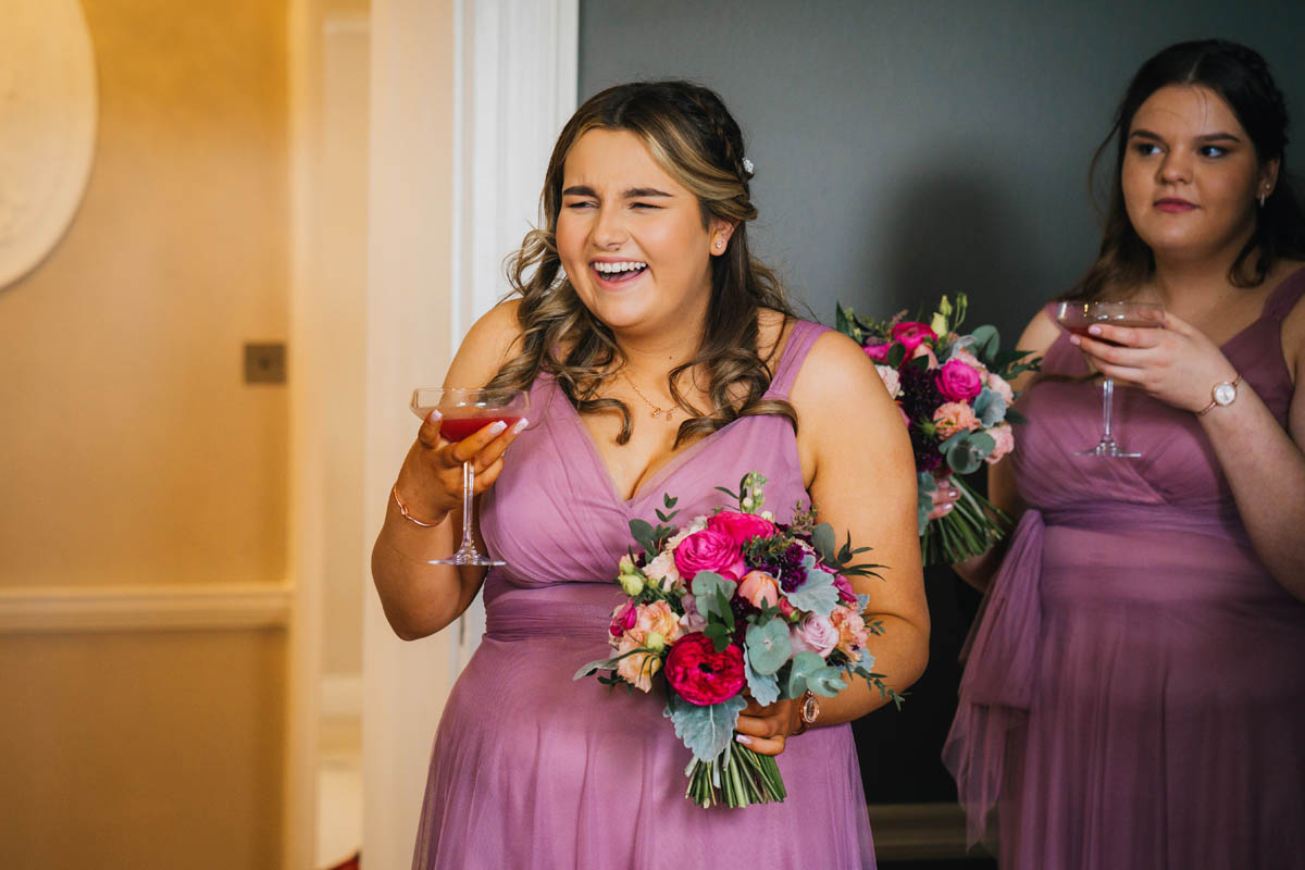 a bridesmaid laughs as she drinks cocktails