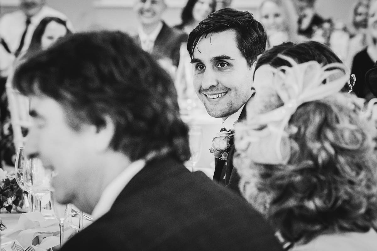 the groom smiles as his best man delivers his speech