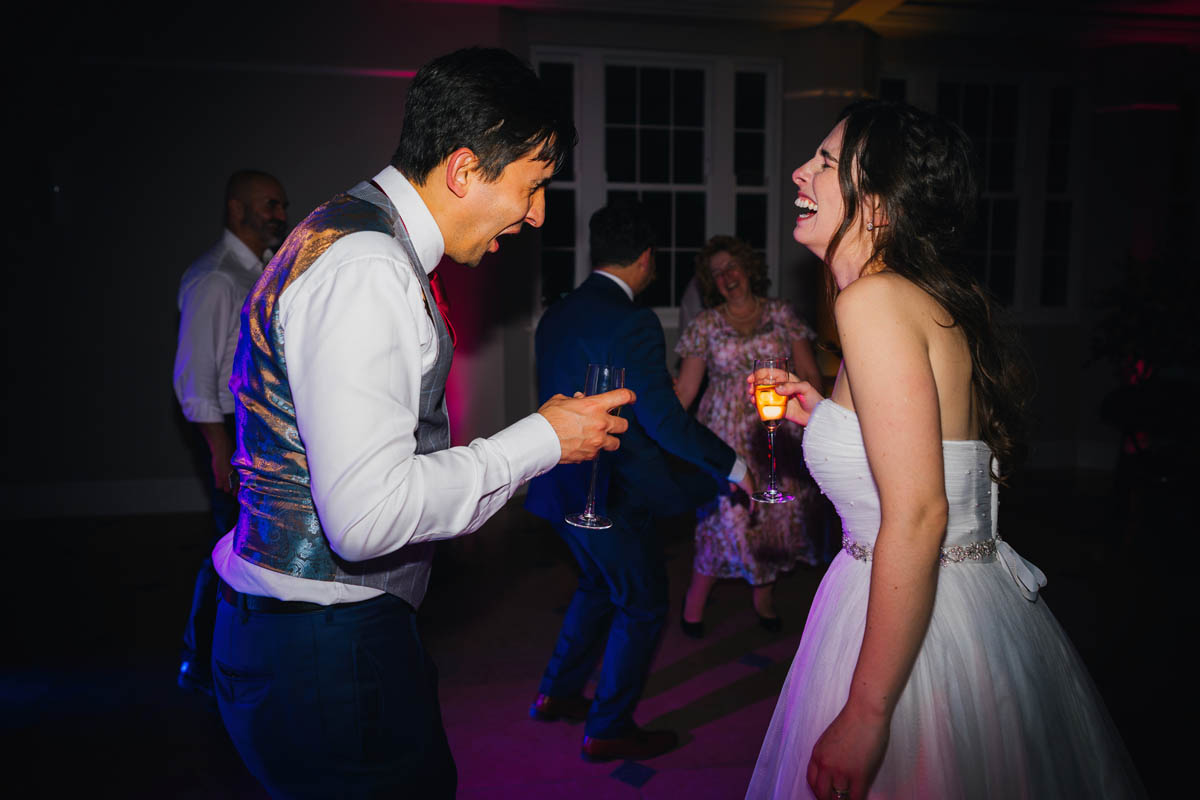the bride laughs as the groom looks disgusted at whatever he has just drank