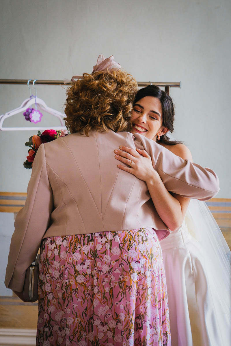 the bride hugs her mother as she is ready for her wedding day