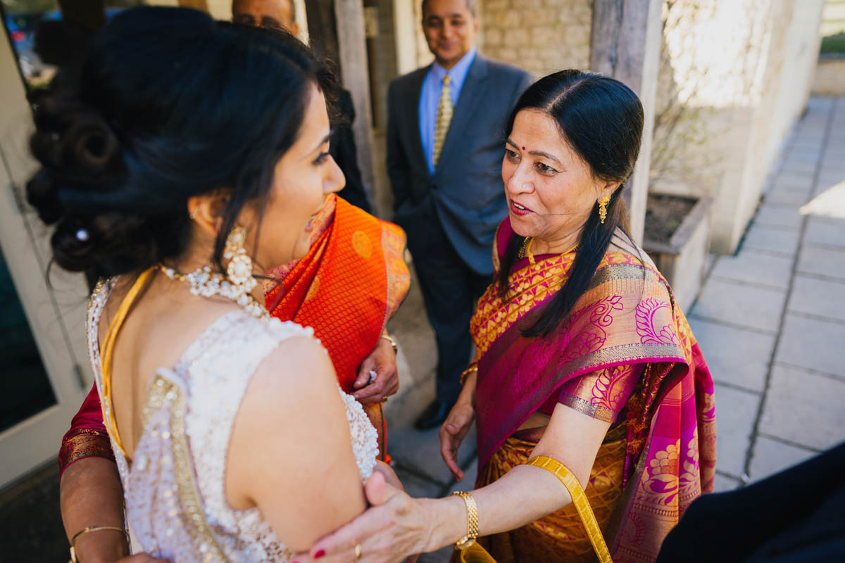 a wedding guests smiles as she touches the bride's arm
