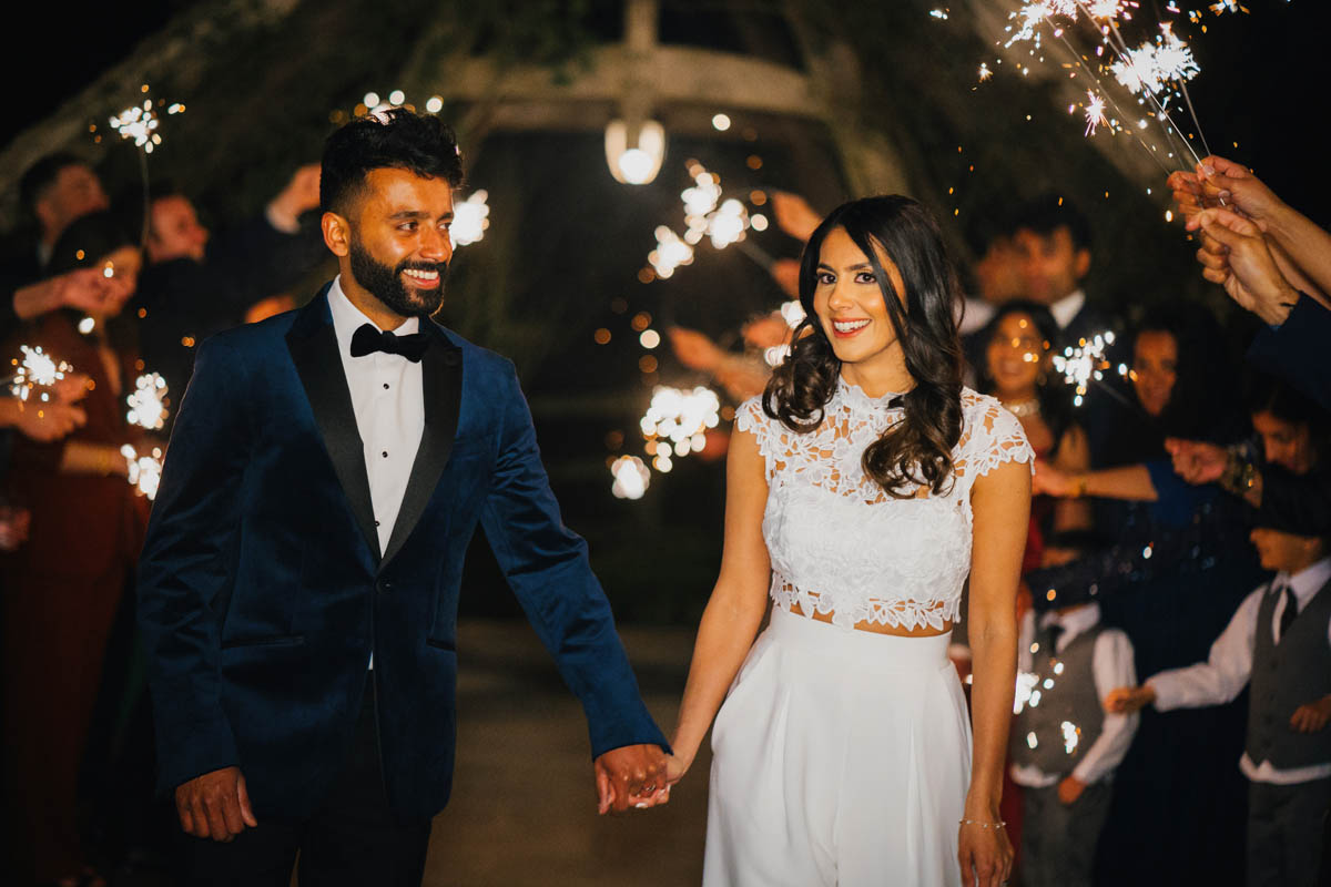 The newly-weds walk through a tunnel of sparklers as wedding guests wave them in the air