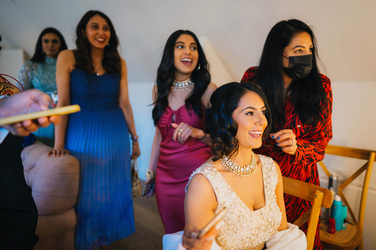 wedding guests laugh with the bride as she gets ready for the day