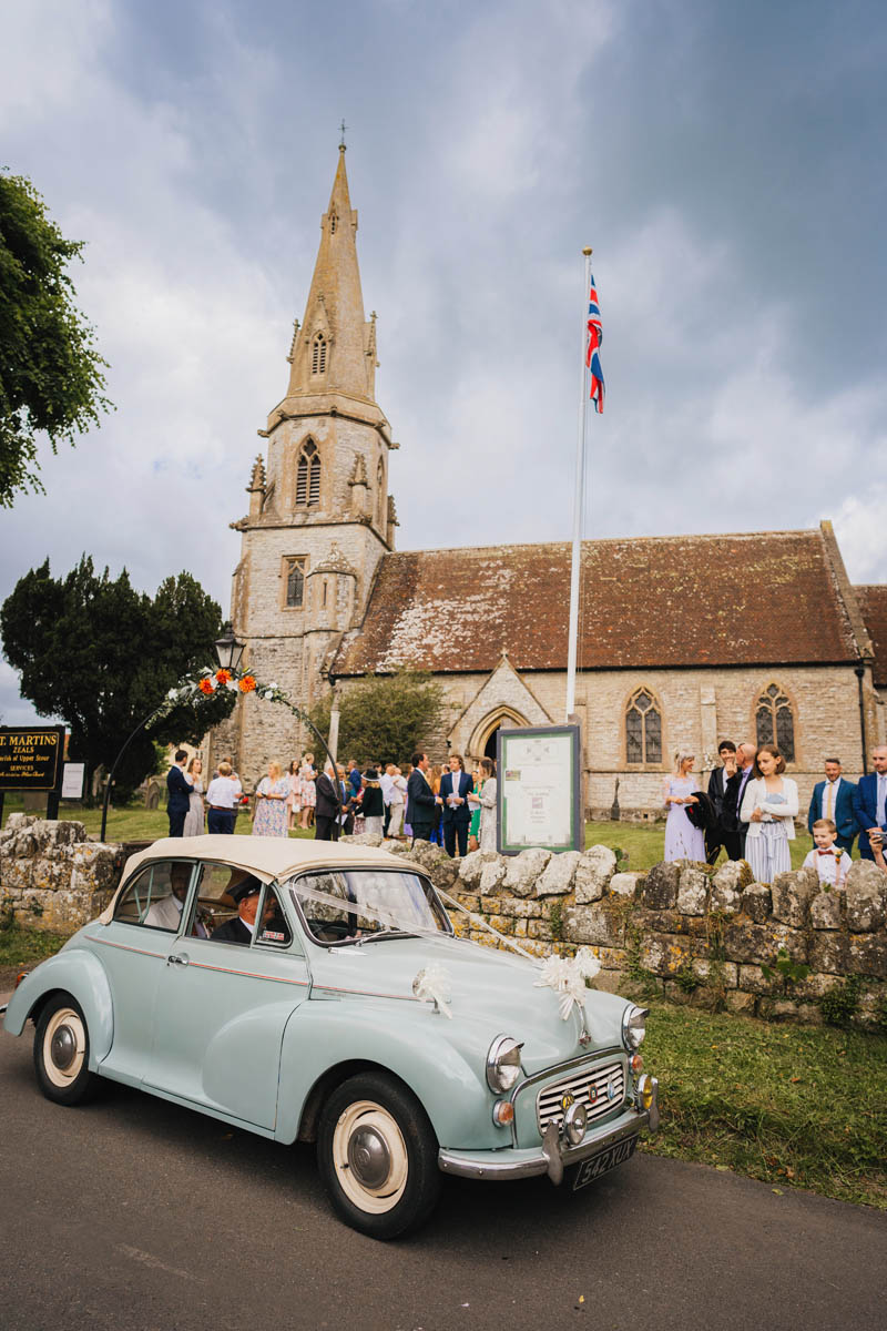 a vintage car leaves the church
