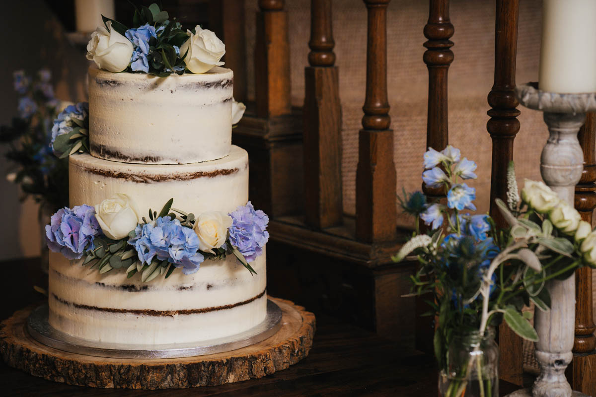 a wedding cake adorned with white roses and blue flowers