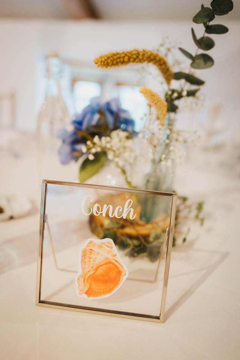 wedding table decorations, flowers and a metal sign with a shell