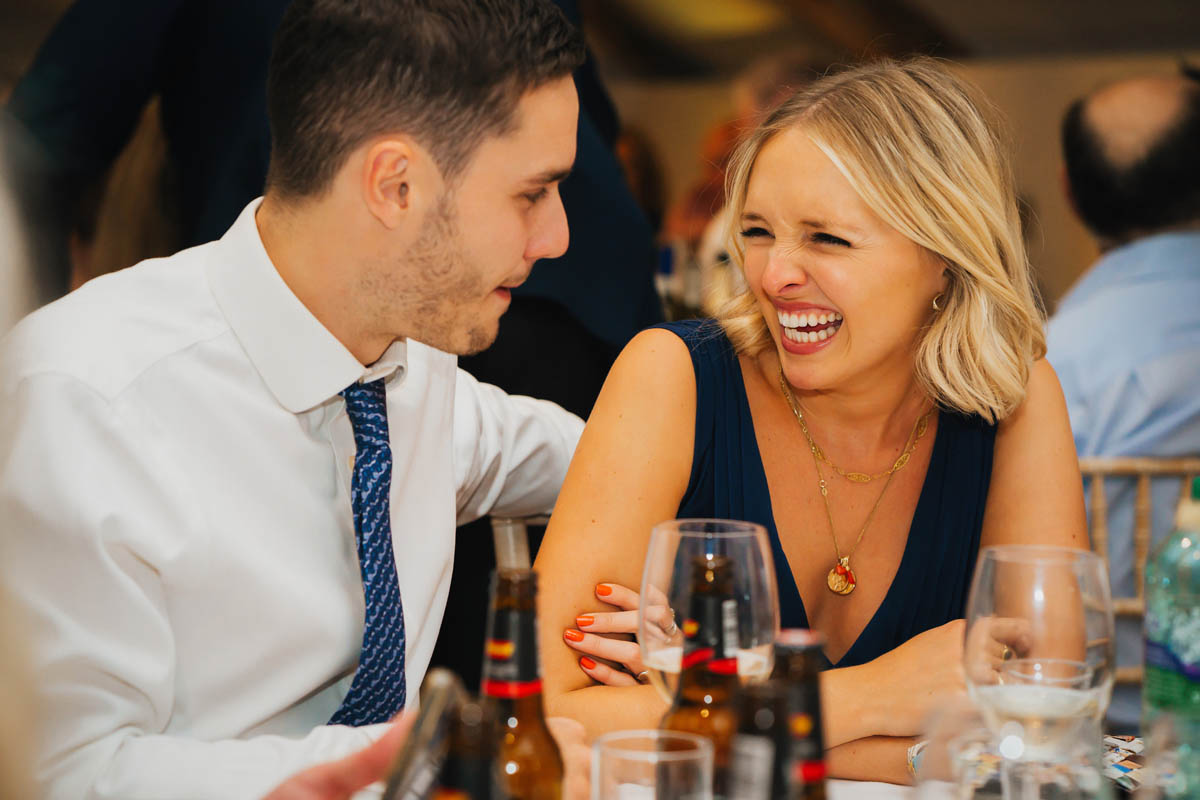 a woman laughs at her partner during the wedding speeches