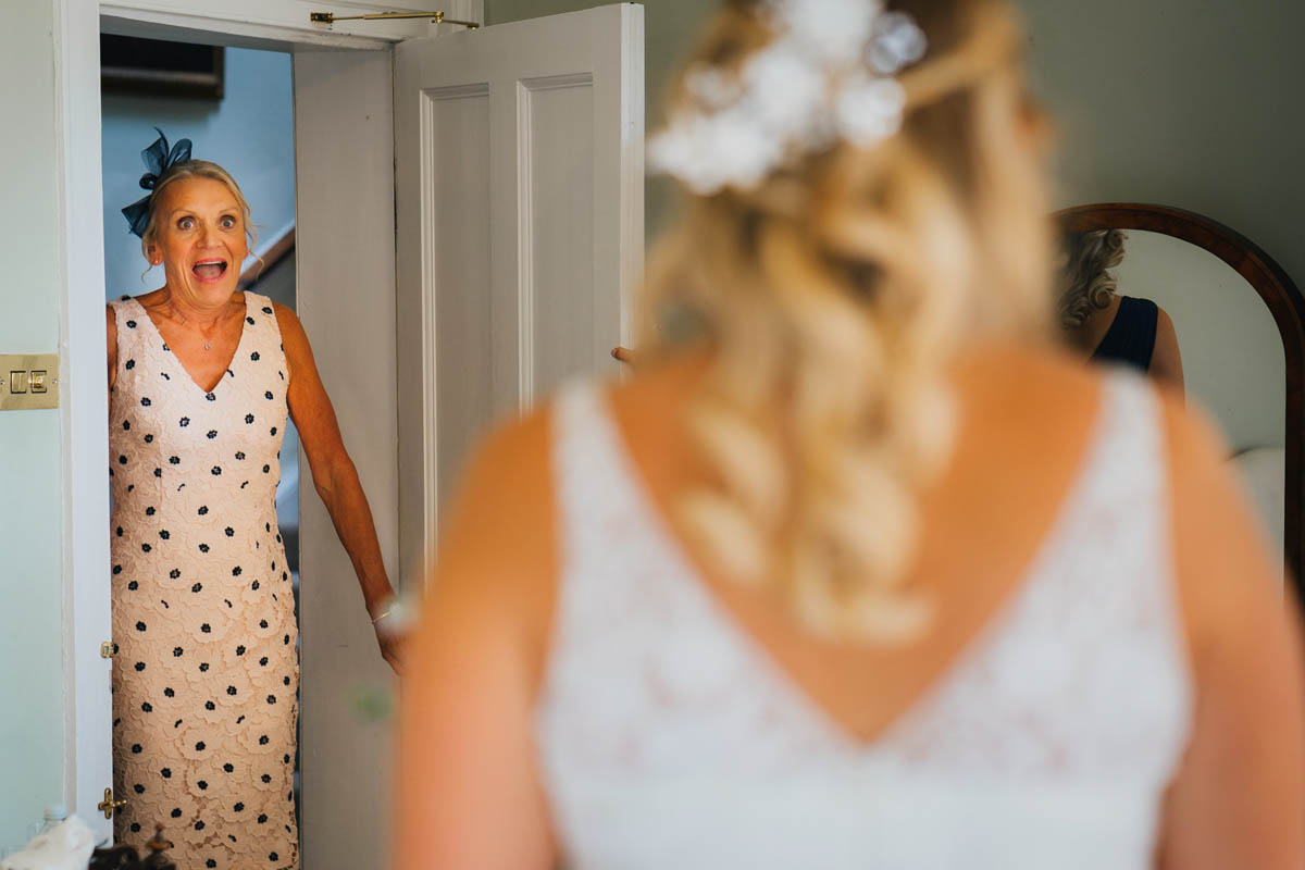 the mother-of-the-bride looks shocked as she see's her daughter in her wedding dress for the first time