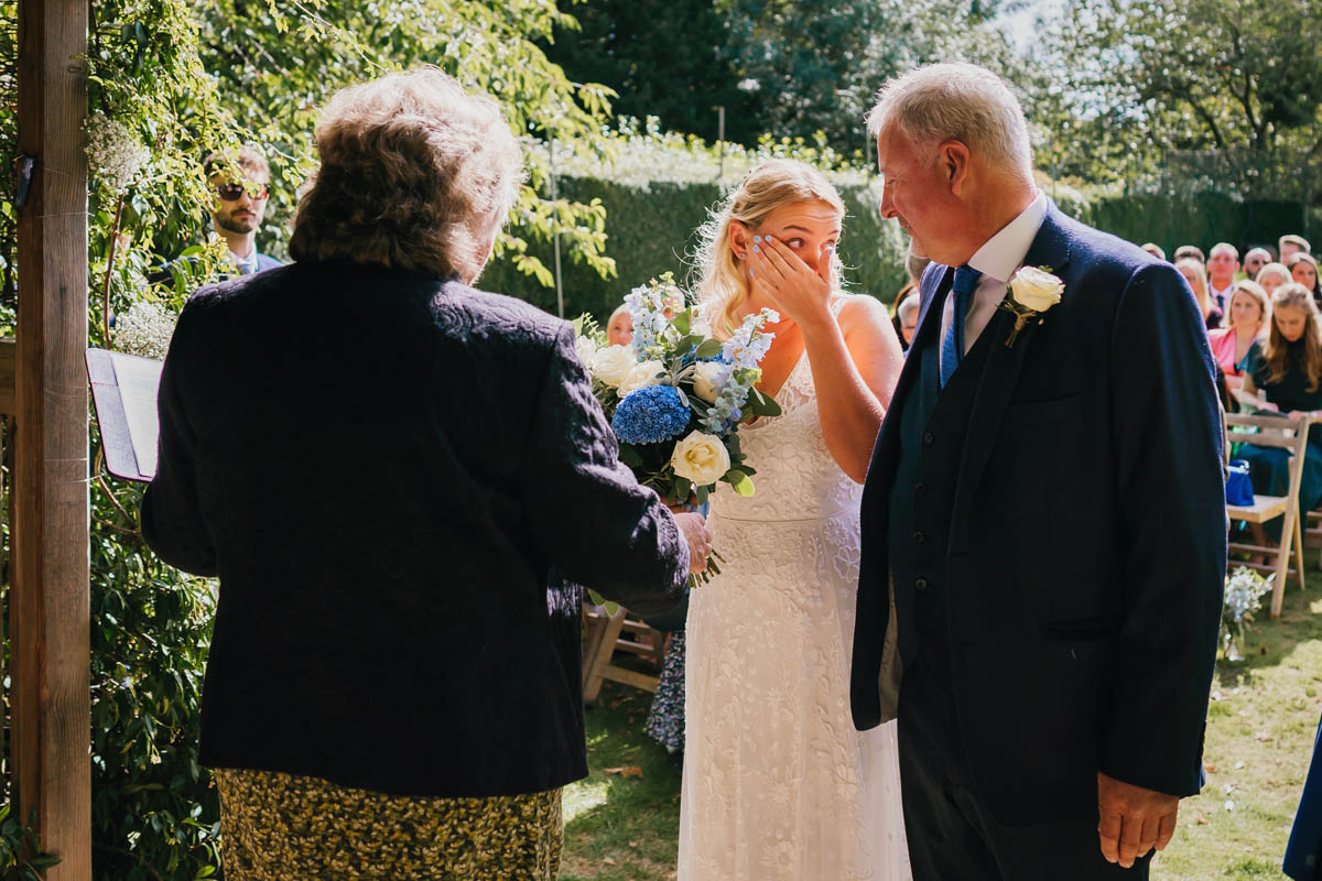 the bride wipes away a tear as her father gives her away