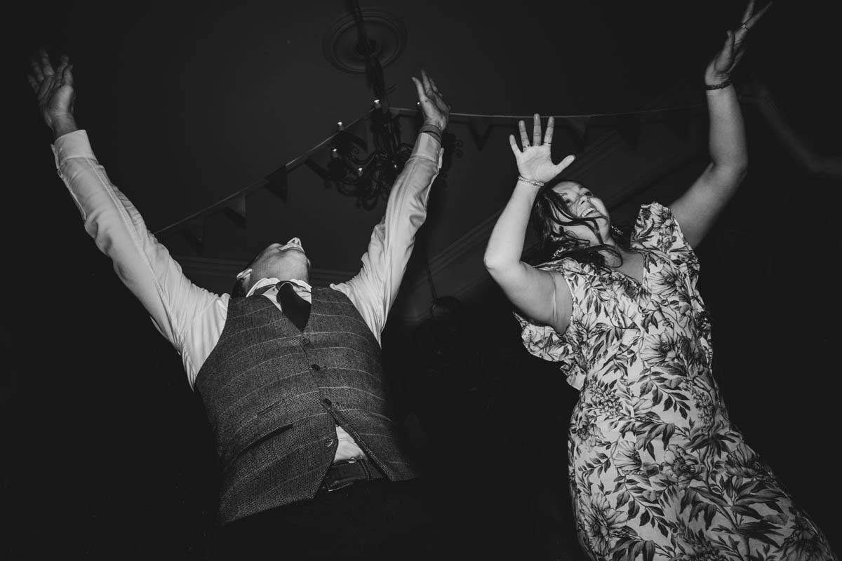 wedding guests throw their arms into the air as they dance