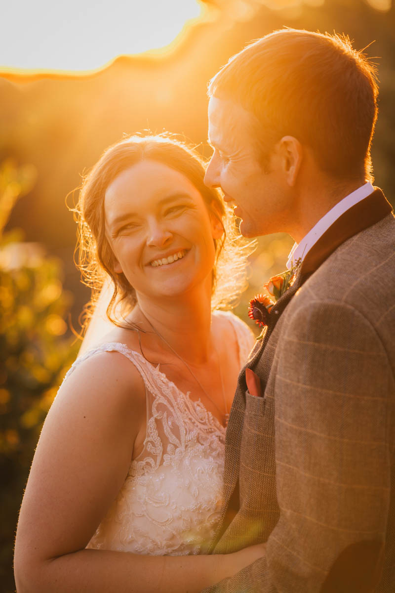 the bride beams with joy as she's back-lit with beautiful golden hour light at sunset