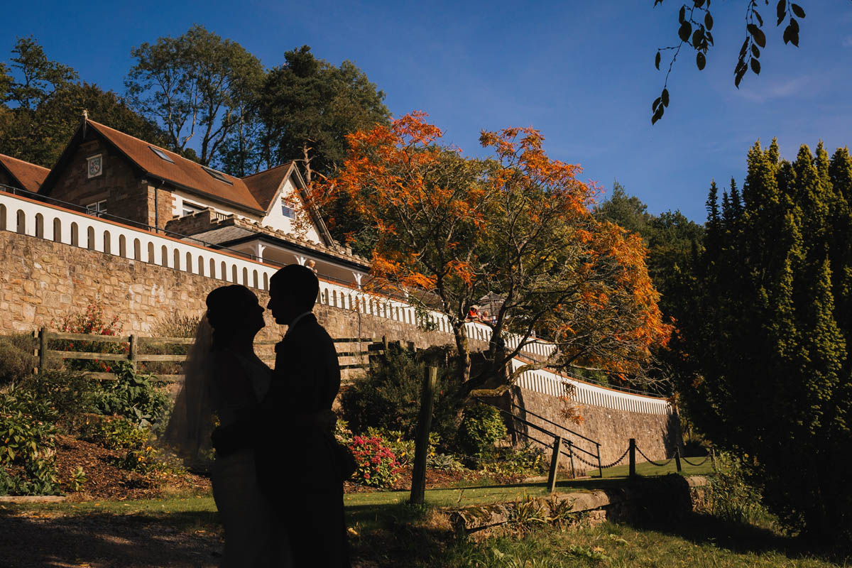 a silhouette of the bride and groom against the autumnal colours of cear llan