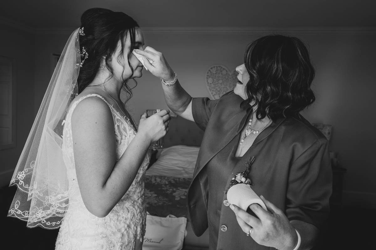 black and white photograph of the bride's mother wiping away her tear