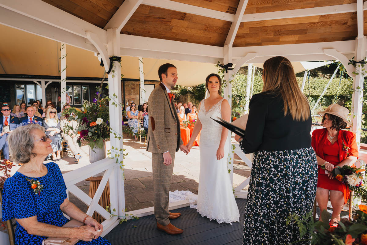 the bride and groom hold hands under the gazebo during their wedding ceremony