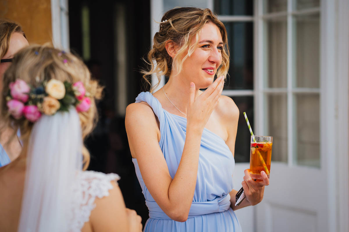 a bridesmaid laughs as she drinks a Pimms during the drinks reception at the wedding
