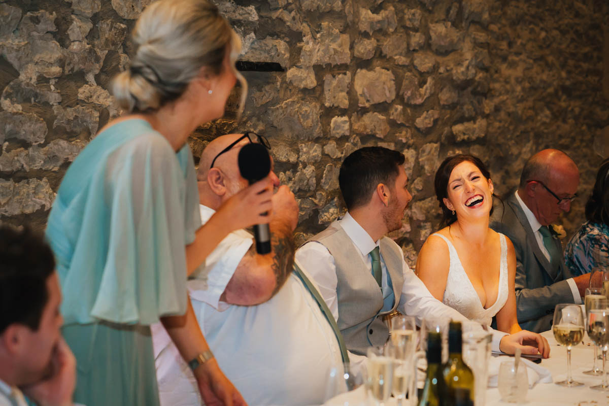 the bride laughs at her bridesmaid's speech