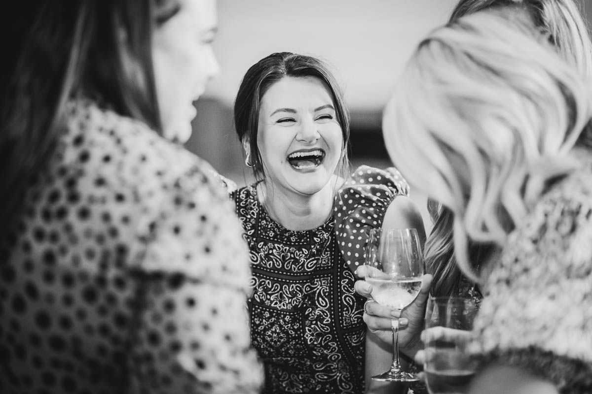 a wedding guest laughs with her friends