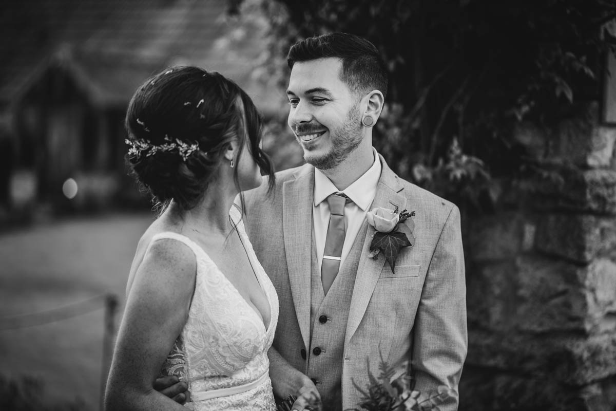 the groom smiles at his new wife in black and white