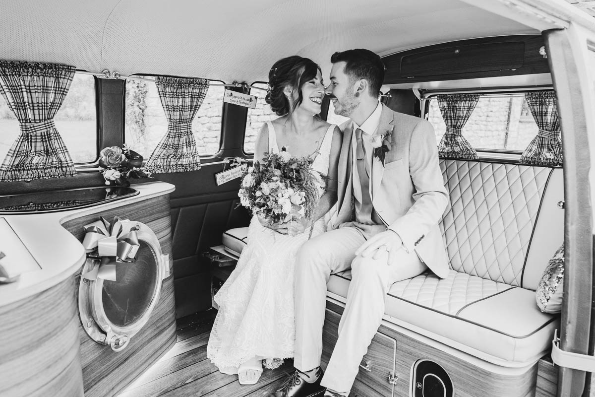 the bride and groom in black and white inside the VW camper