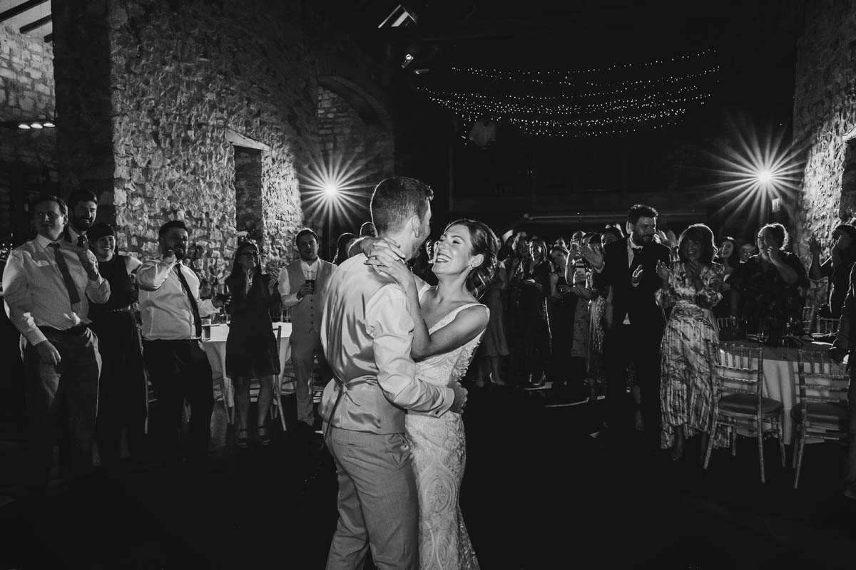the first dance in black and white. off-camera flash fires behind the newly weds