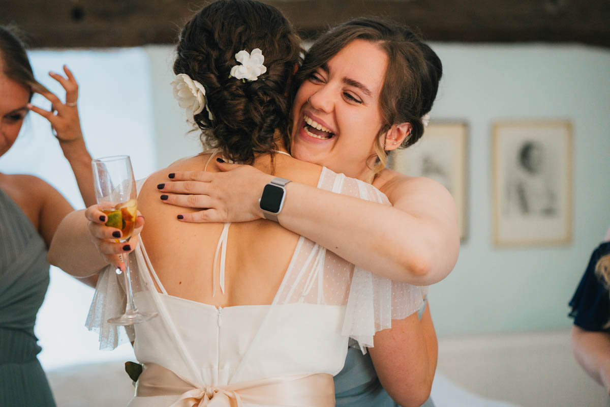 a bridesmaid hugs the bride