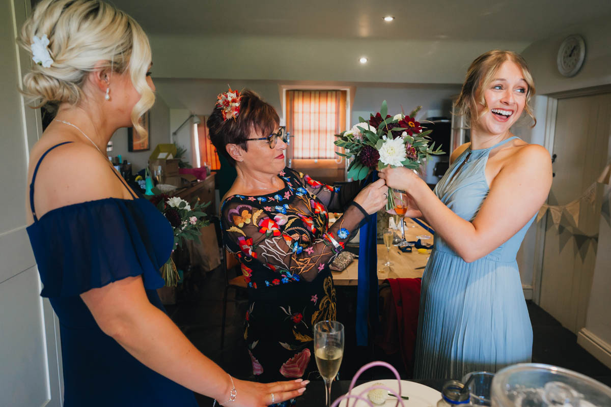 the mother of the bride and two bridesmaids tie the wedding bouquets