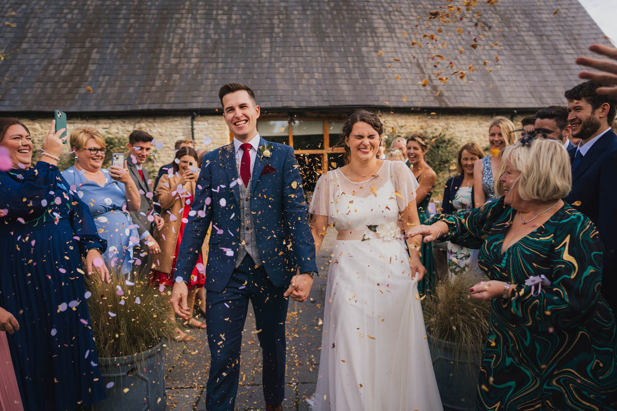 the bride and groom walk down an aisle of guests as their wedding guests shower them in confetti