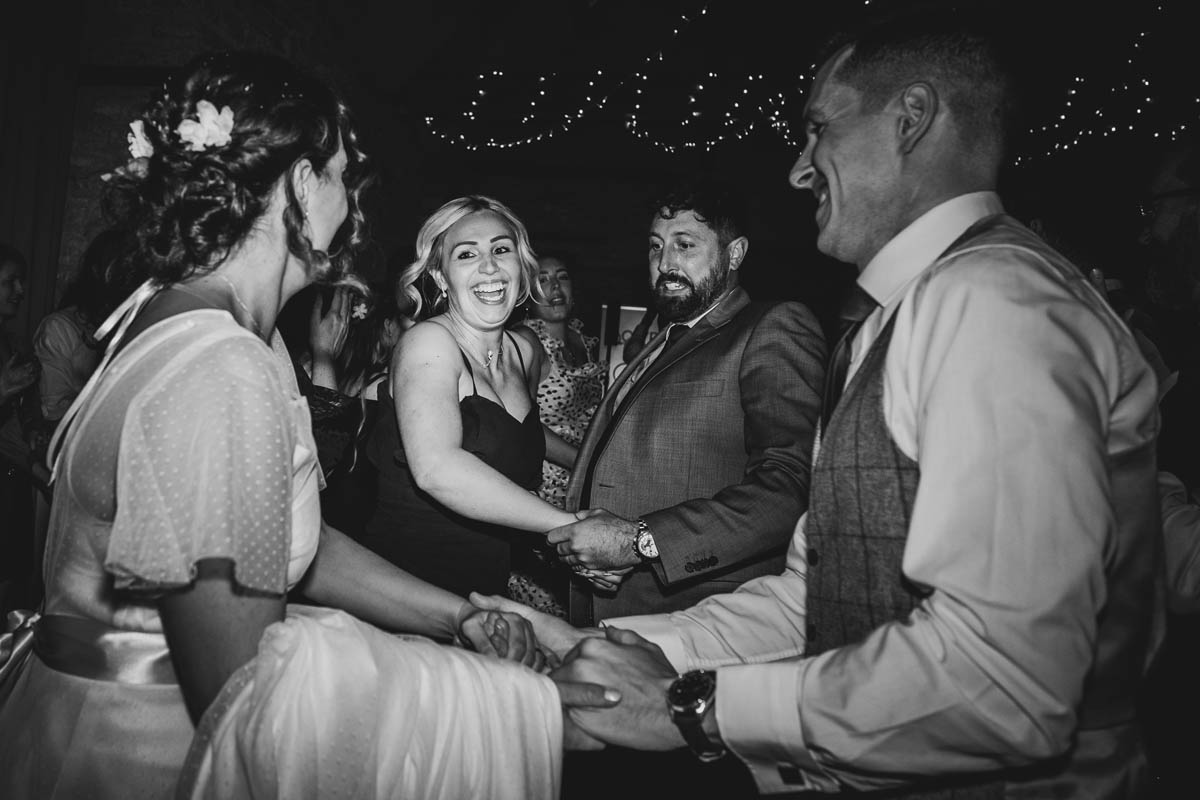 black and white photograph of wedding guests dancing towards the bride and groom in a ceilidh