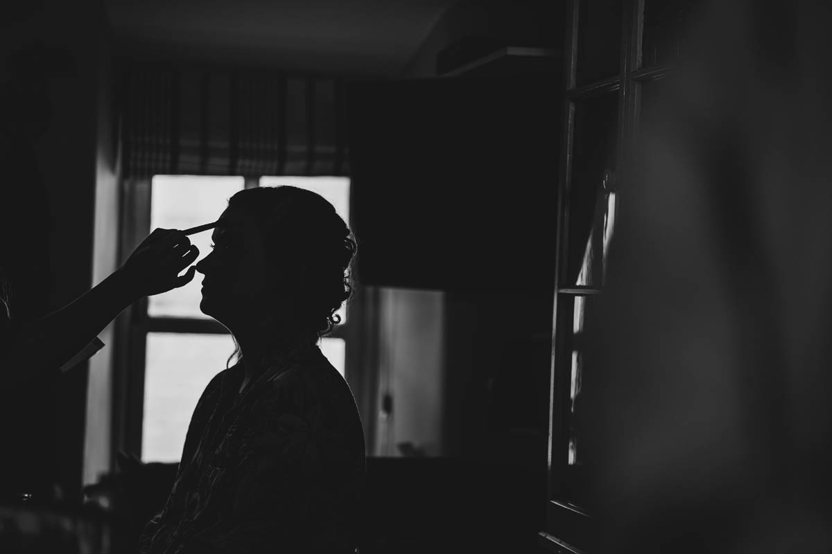 a black and white silhouette of the bride having her make-up applied