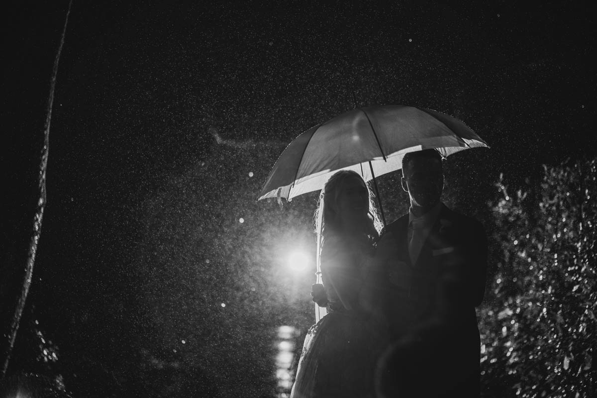 black and white portrait of the bride and groom kissing in the rain