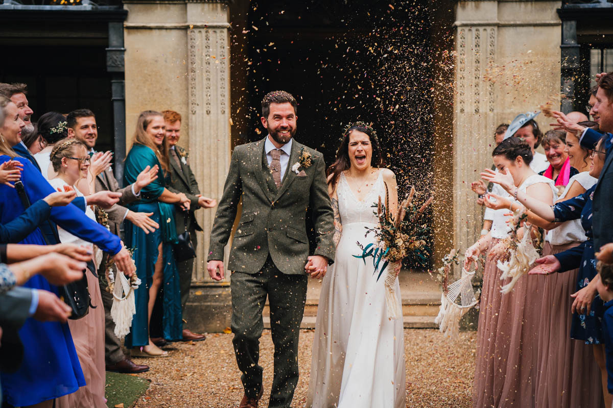 wedding guests throw dried flower confetti over the newly-married couple