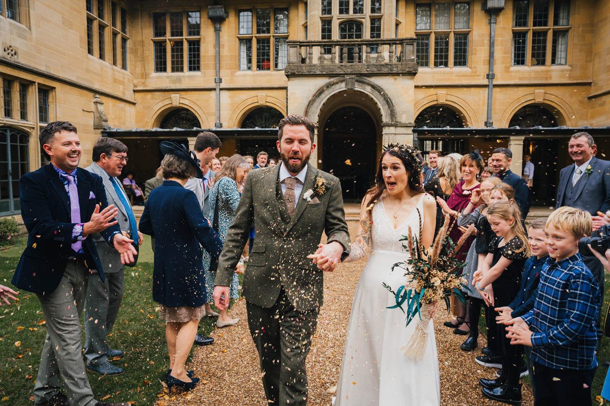 the newly-weds pull funny faces as their guests cover them in confetti