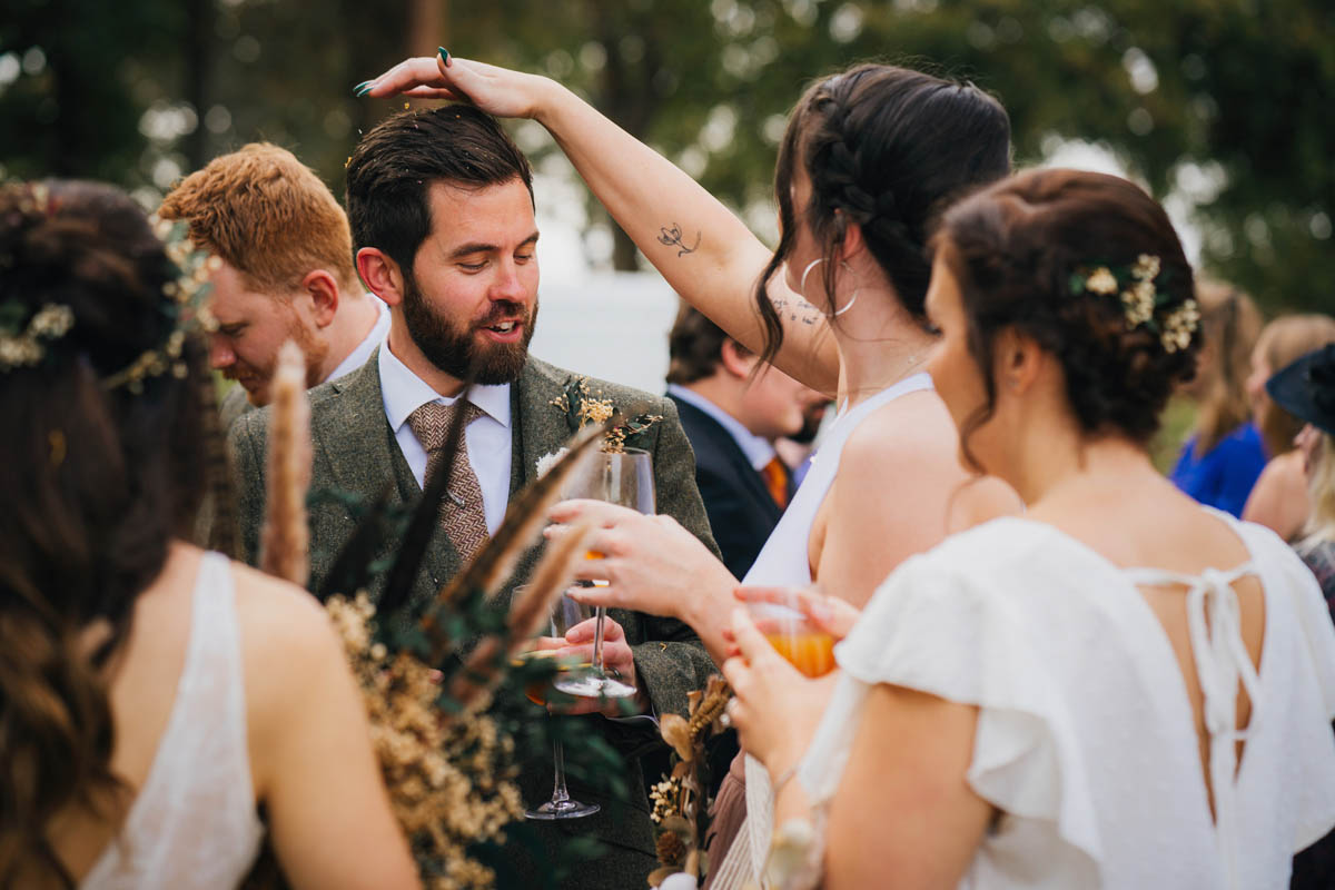 a bridesmaid takes confetti out of the groom's hair