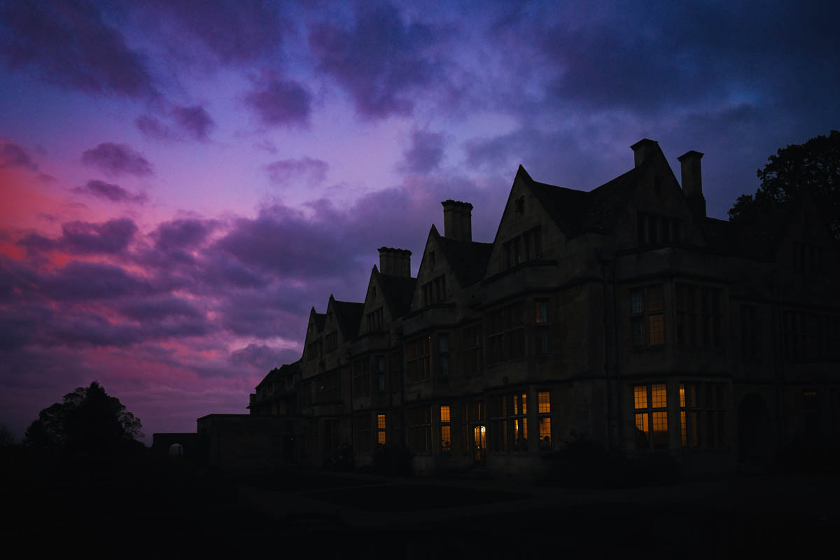 silhouette of the wedding venue against a darkening, pink sky