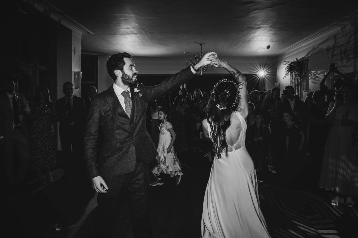 the first dance in black and white, the groom spins his bride around the dance floor