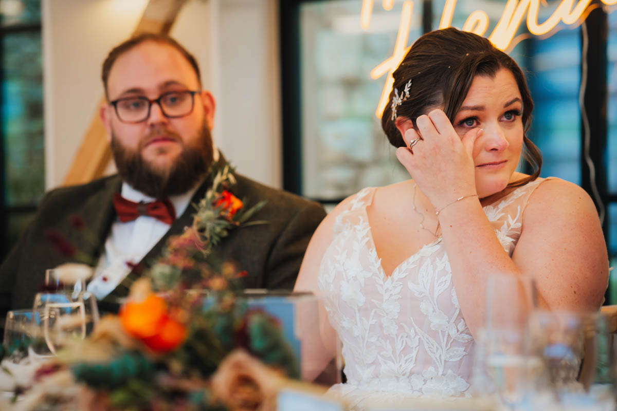 bride wipes away a tear during the wedding speeches
