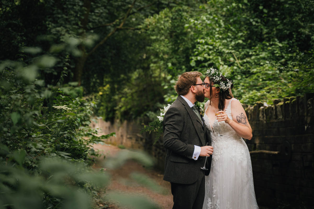 newly weds kiss whilst holding champagne immediately after their Arnos Vale wedding ceremony