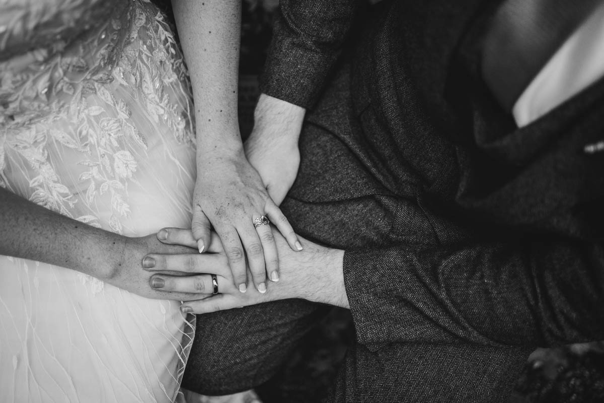 the bride and groom holding hands with their wedding rings, in black and white