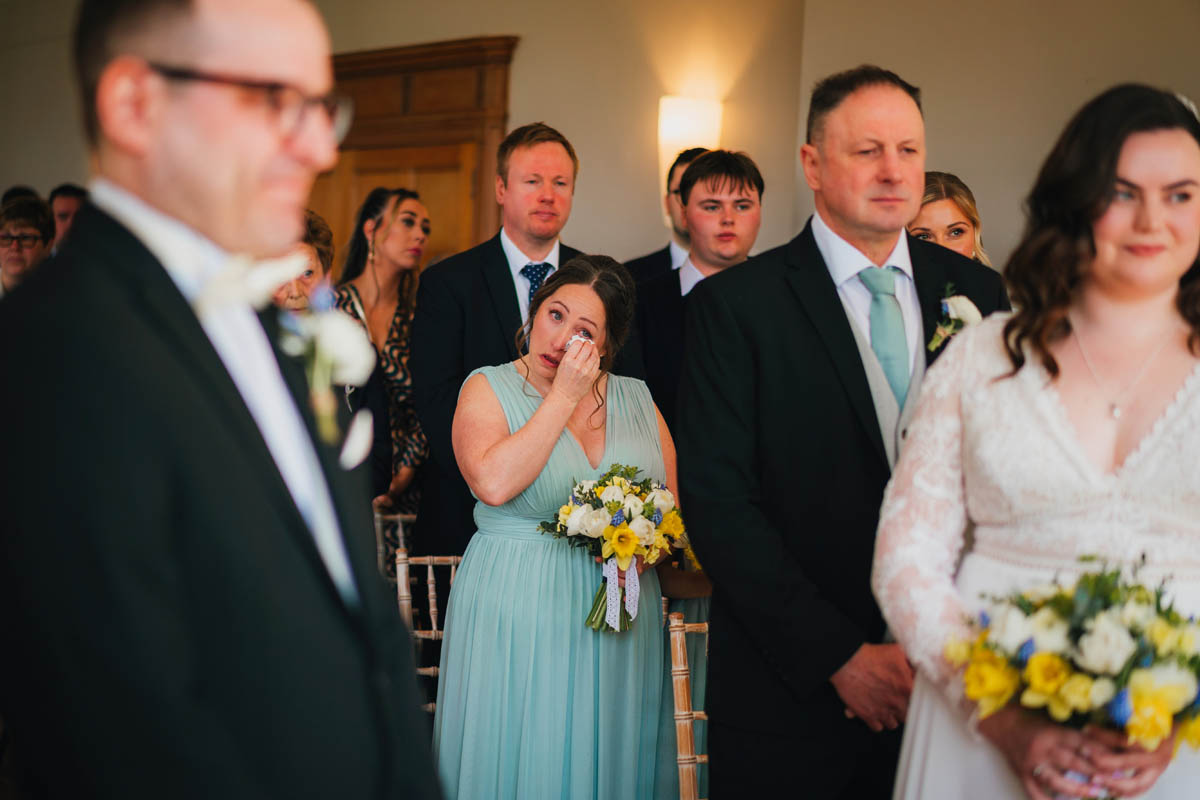 a bridesmaid wipes away a happy tear during the wedding ceremony