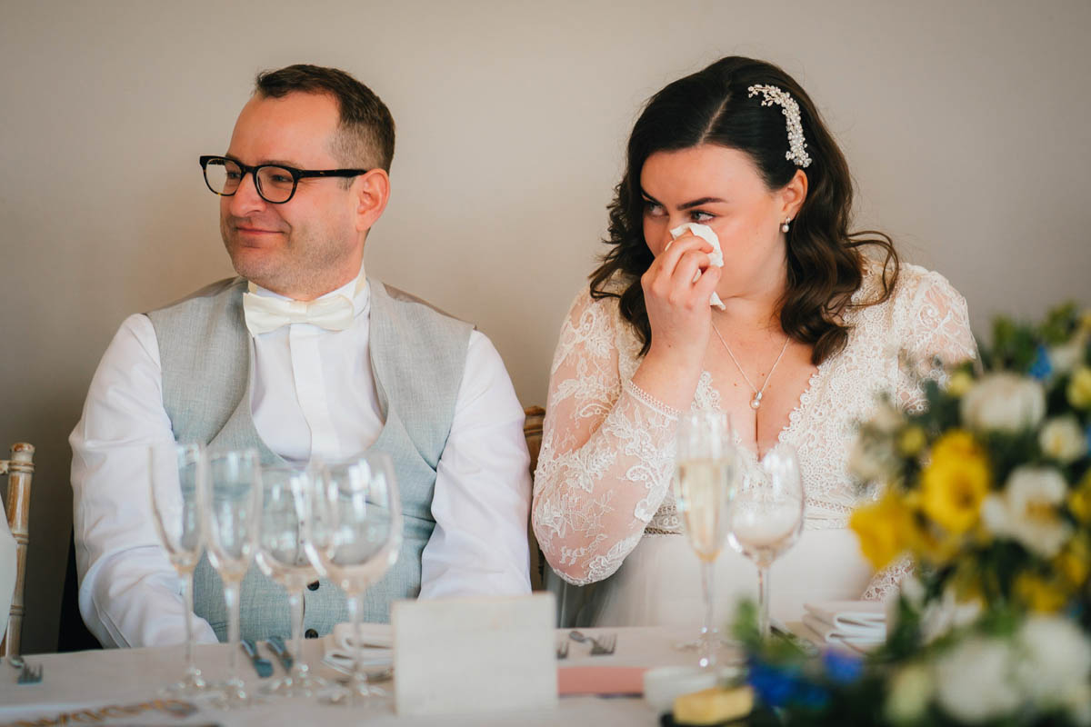 a bride wipes away a tear during her wedding speeches