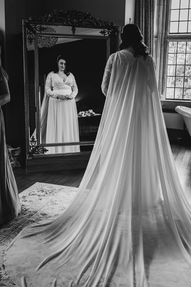 black and white photograph of the bride looking at herself in the mirror at Coombe Lodge