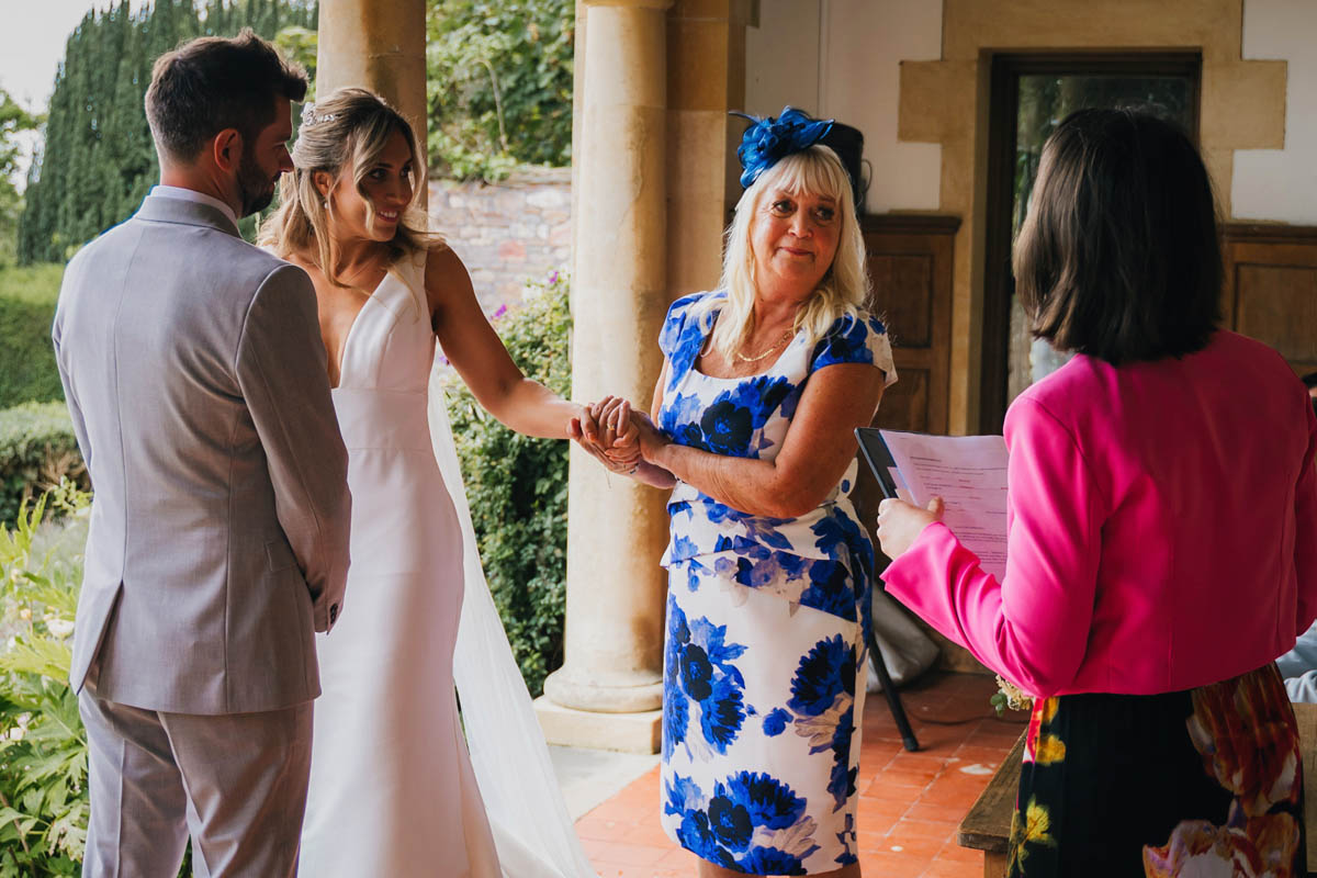 the mother of the bride looks emotional as she holds her daughter's hand during the wedding speeches