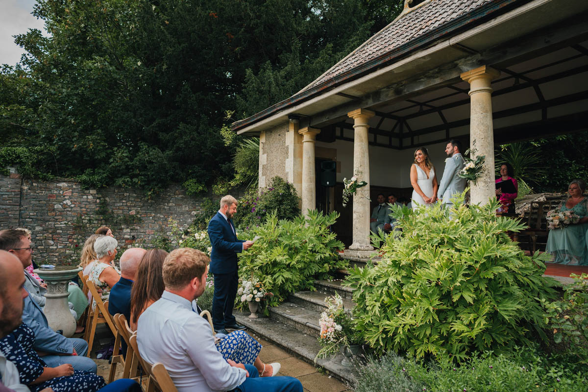 a man performs a reading during the wedding ceremony at barley wood