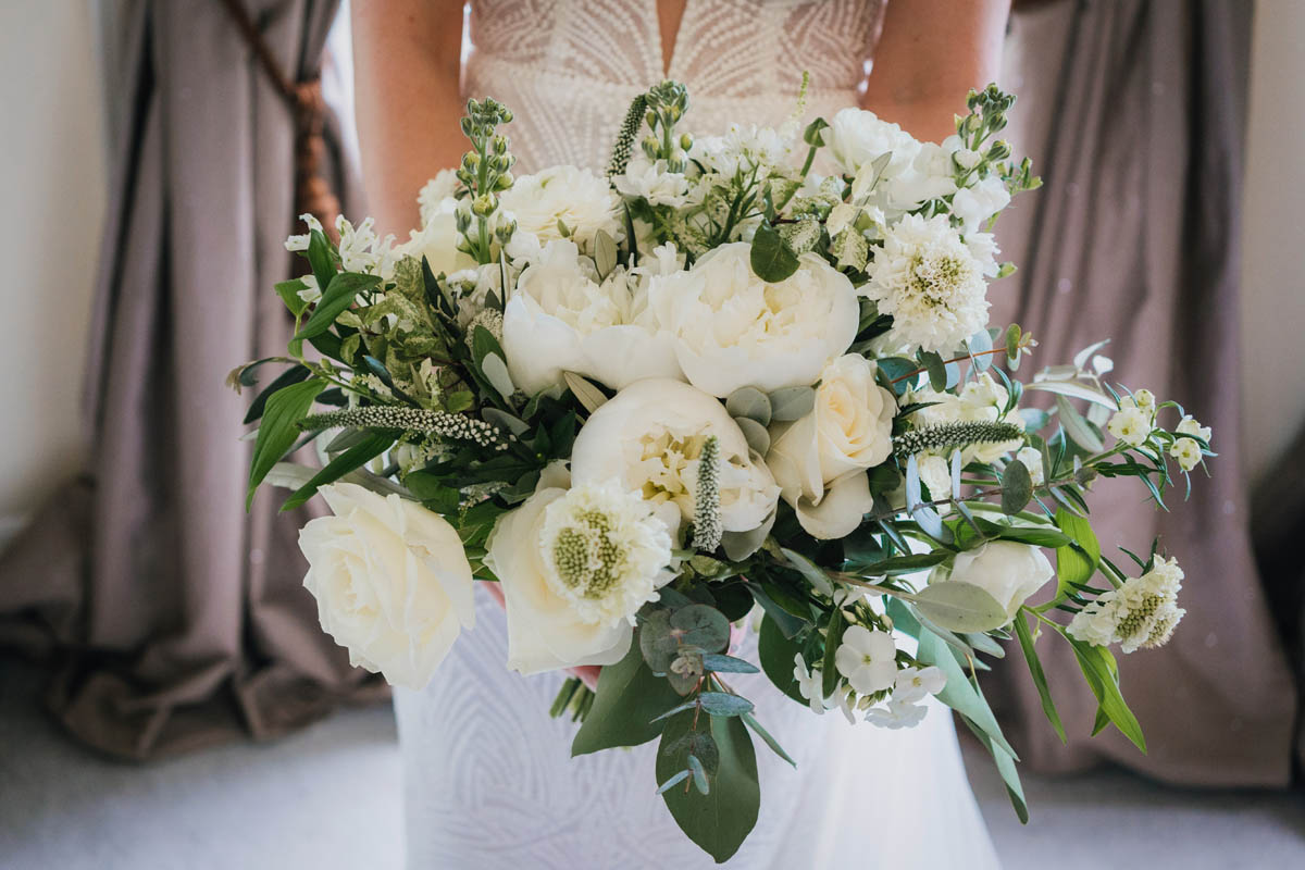 the bridal bouquet which contains eucalyptus, white roses and other green foliage