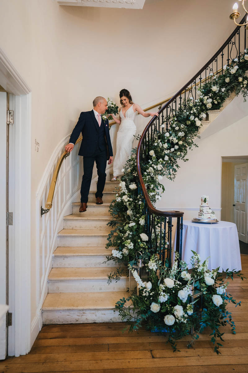 the bride and her father walk down the spiral staircase