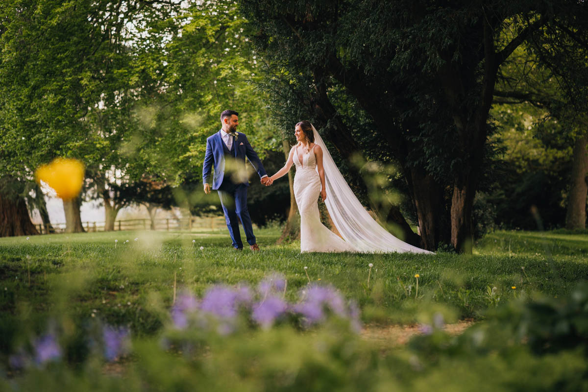 the groom leads his bride through the ground of the Gloucestershire wedding venue