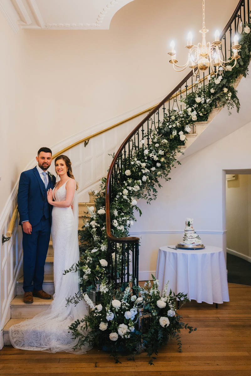 the bride and groom stood at the base of the spiral stair case at eastington park