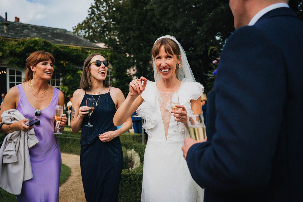 the bride and wedding guests laugh during the drinks reception