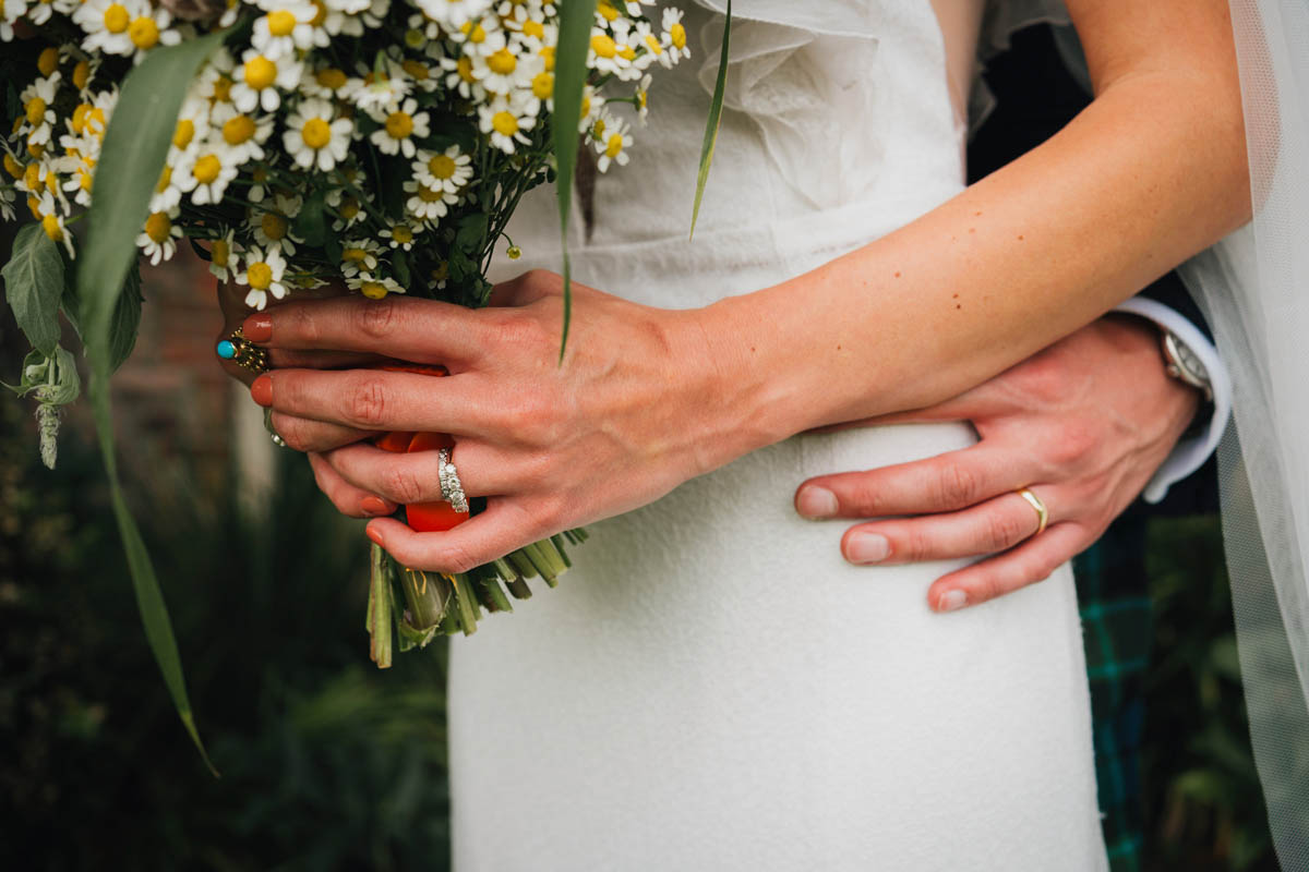 close up of the bride and groom's hands, the wedding bouquet and wedding rings